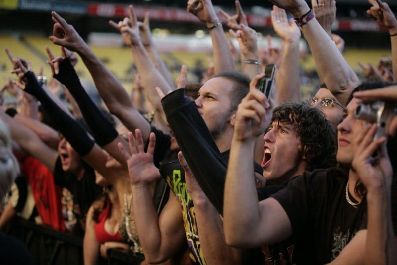 Audience members smiling and reacting during a live stadium performance.