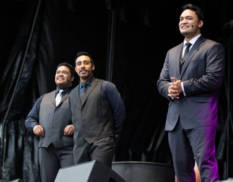 Sol3 Mio performing live on stage in formal suits.