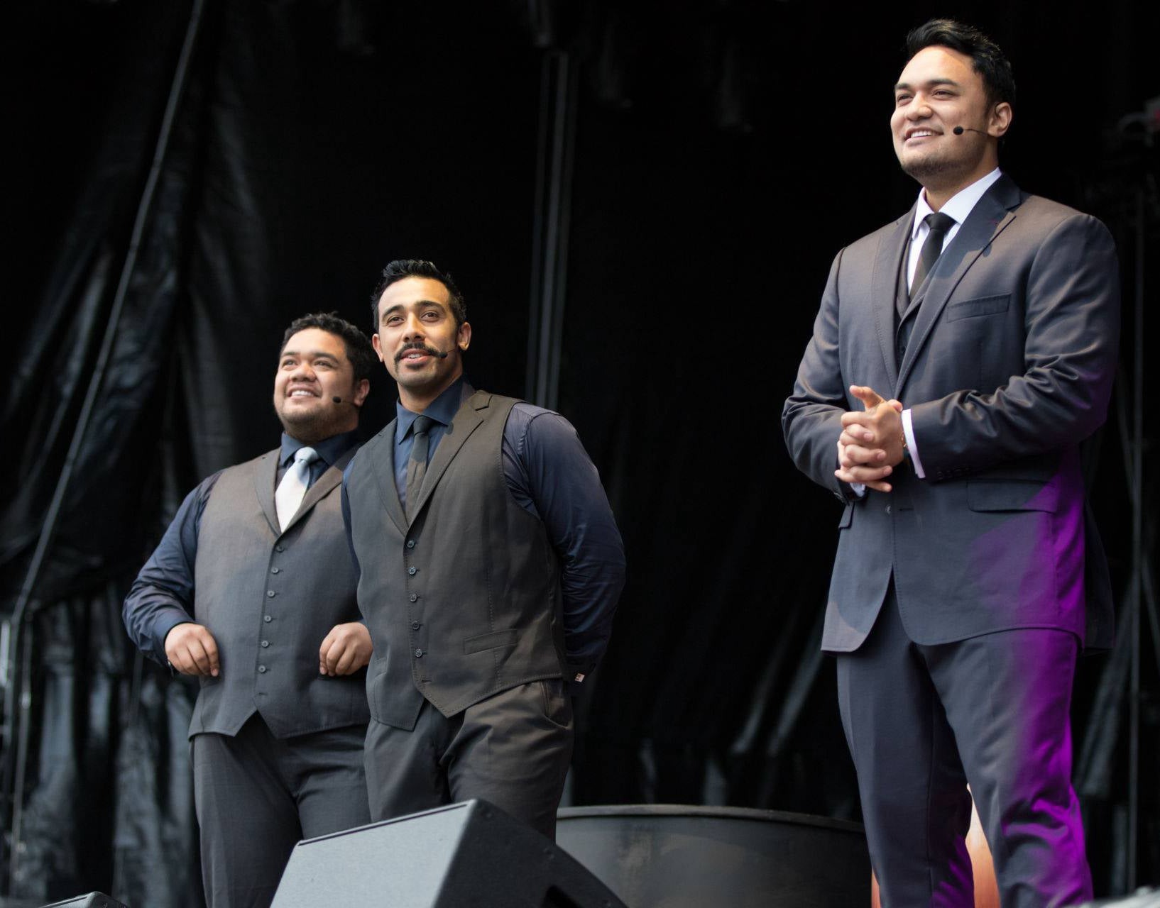 Sol3 Mio performing live on stage in formal suits.